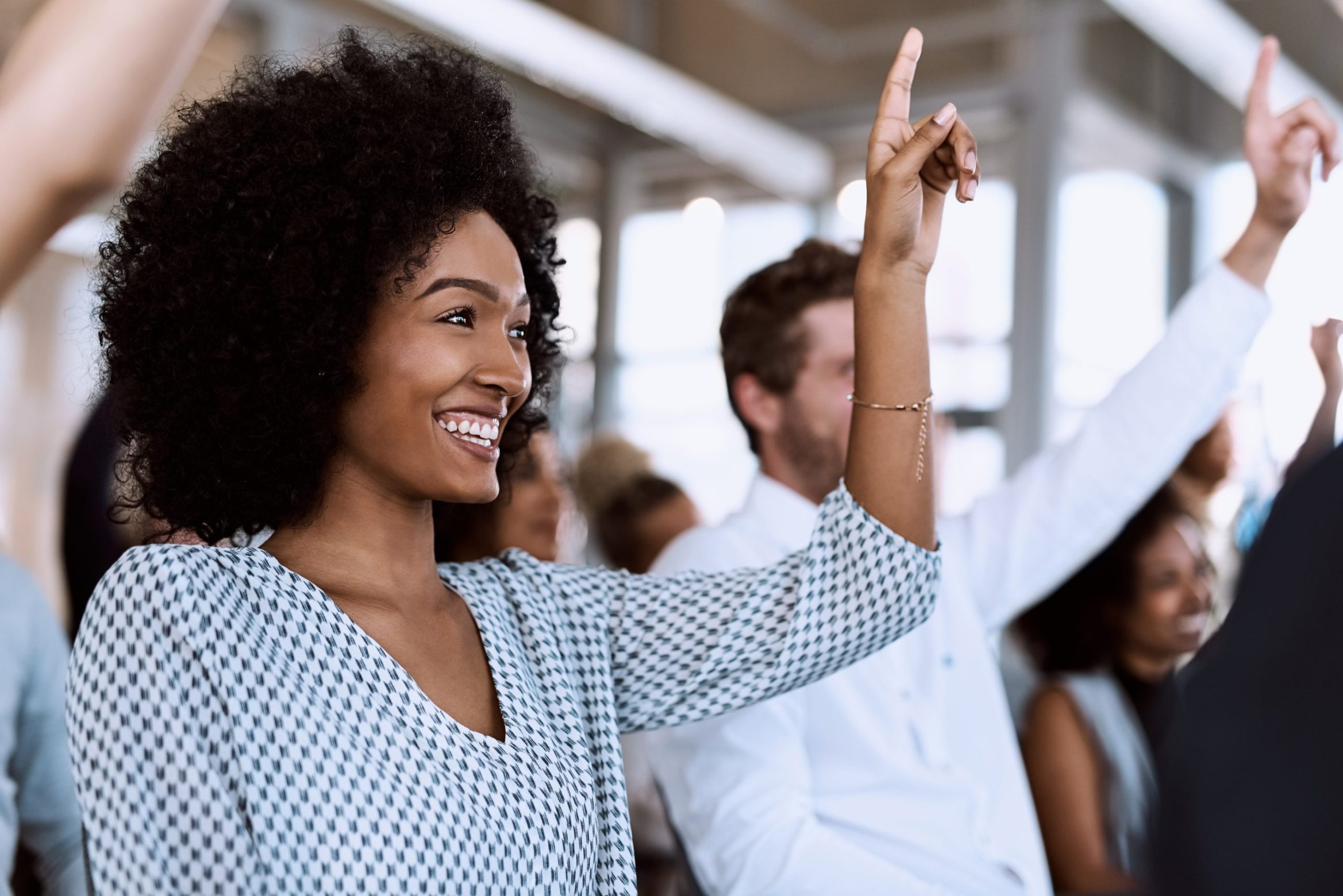 Shot of a group of businesspeople raising their hands to ask questions during a conference.